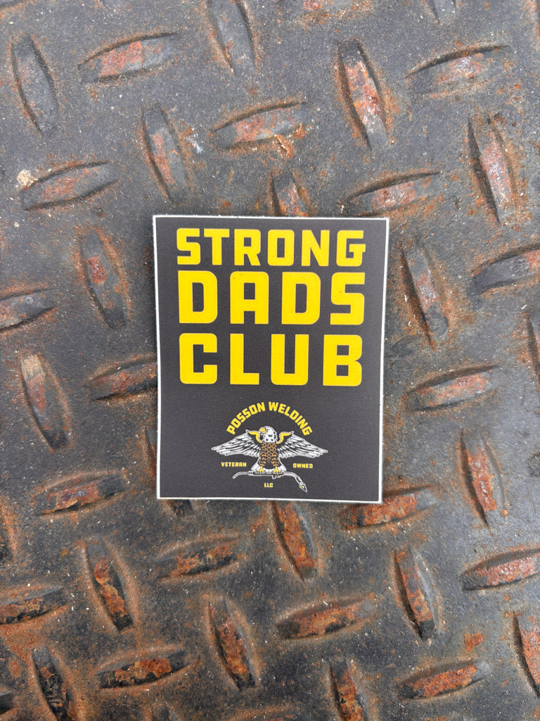 Sticker with 'Strong Dads Club' text on a textured metal surface