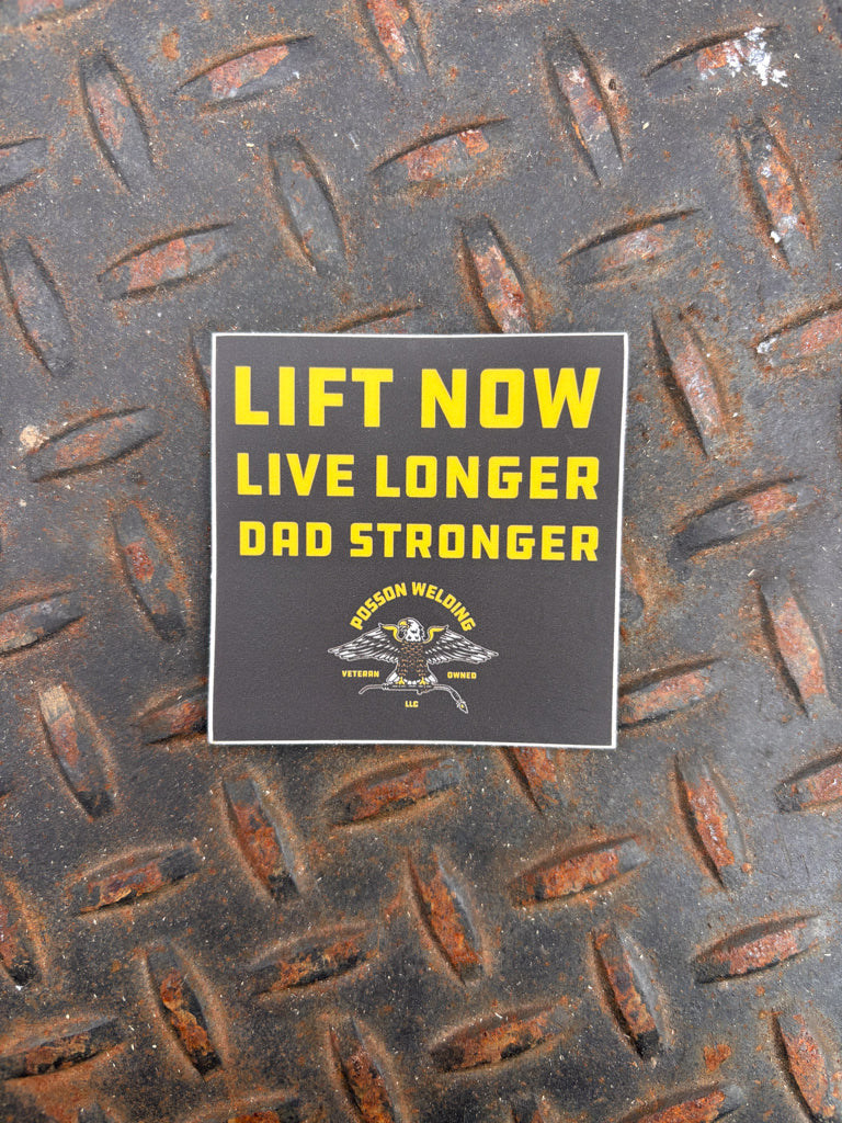 Sticker with 'Lift Now Live Longer, Dad Stronger' text on a textured metal surface.